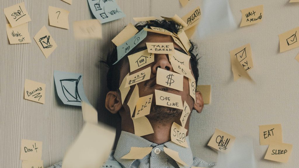 Man with post it notes covering his head and the space on the wall around him.