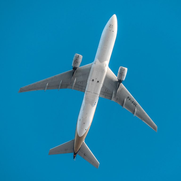 An aeroplane flying through a bright blue sky.
