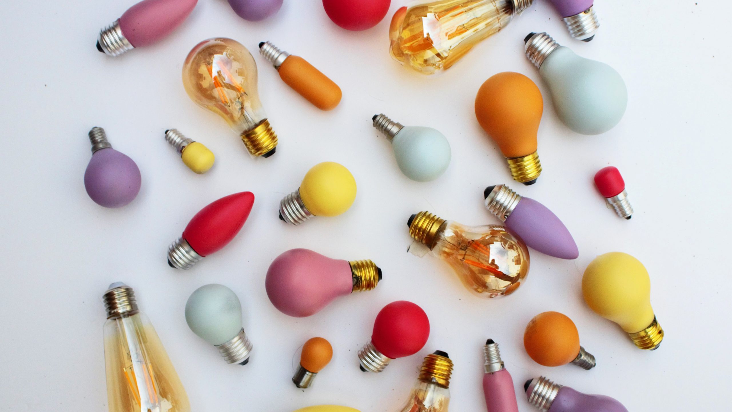 Flatlay photograph featuring brightly coloured lightbulbs in different shapes and sizes.