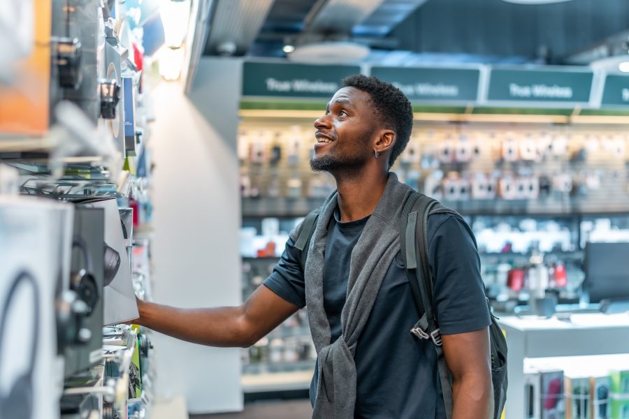 Smiling shopper browsing headphones in an electronics store, for a blog on why customers leave loyalty programmes